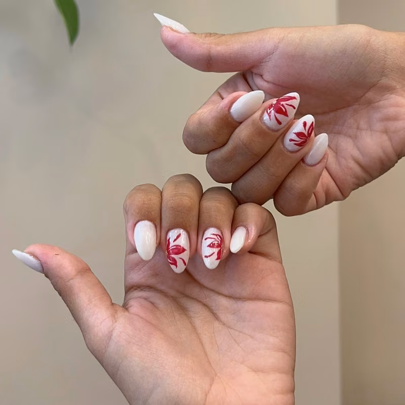 Uñas blancas con flores rojas pintadas a mano